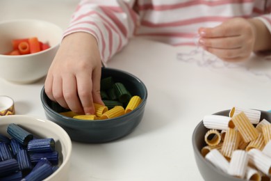 Photo of Little girl making craft at white table, closeup. Child creativity and handmade handicraft