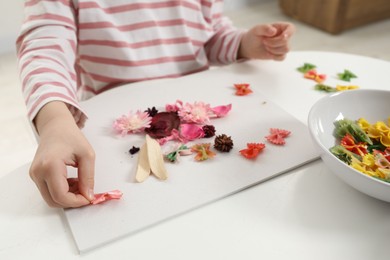 Photo of Little girl making craft at white table indoors, closeup. Child creativity and handmade handicraft