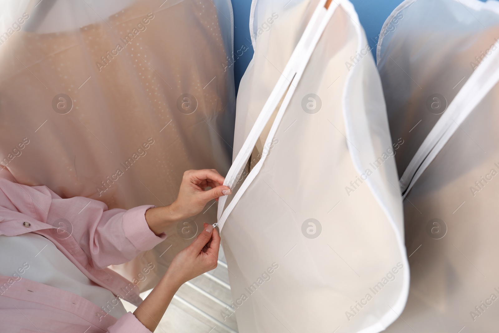 Photo of Woman zipping garment cover with clothes indoors, above view