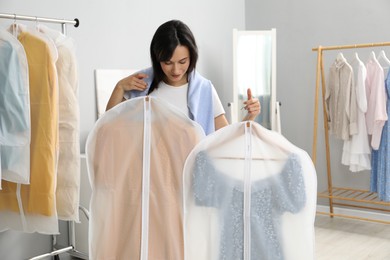 Woman holding garment covers with clothes indoors