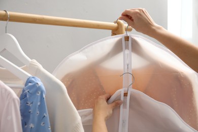 Photo of Woman holding garment covers with clothes indoors, closeup