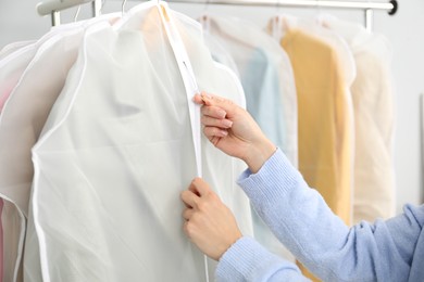 Photo of Woman zipping garment cover with clothes indoors, closeup