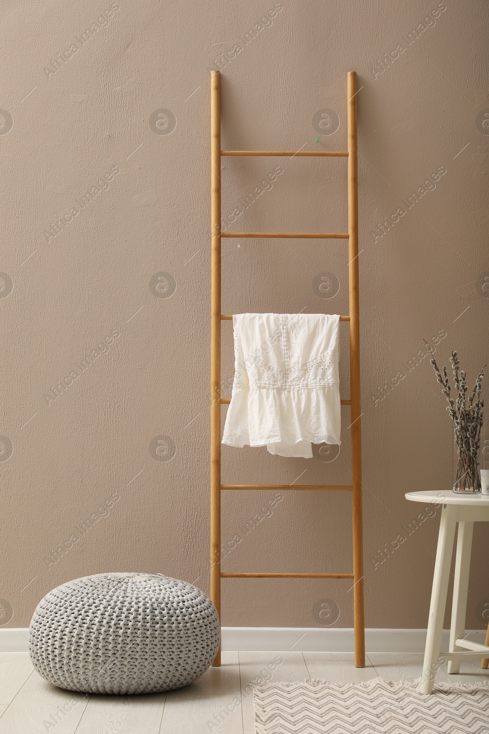 Photo of Stylish room interior with pouf, ladder and decor elements