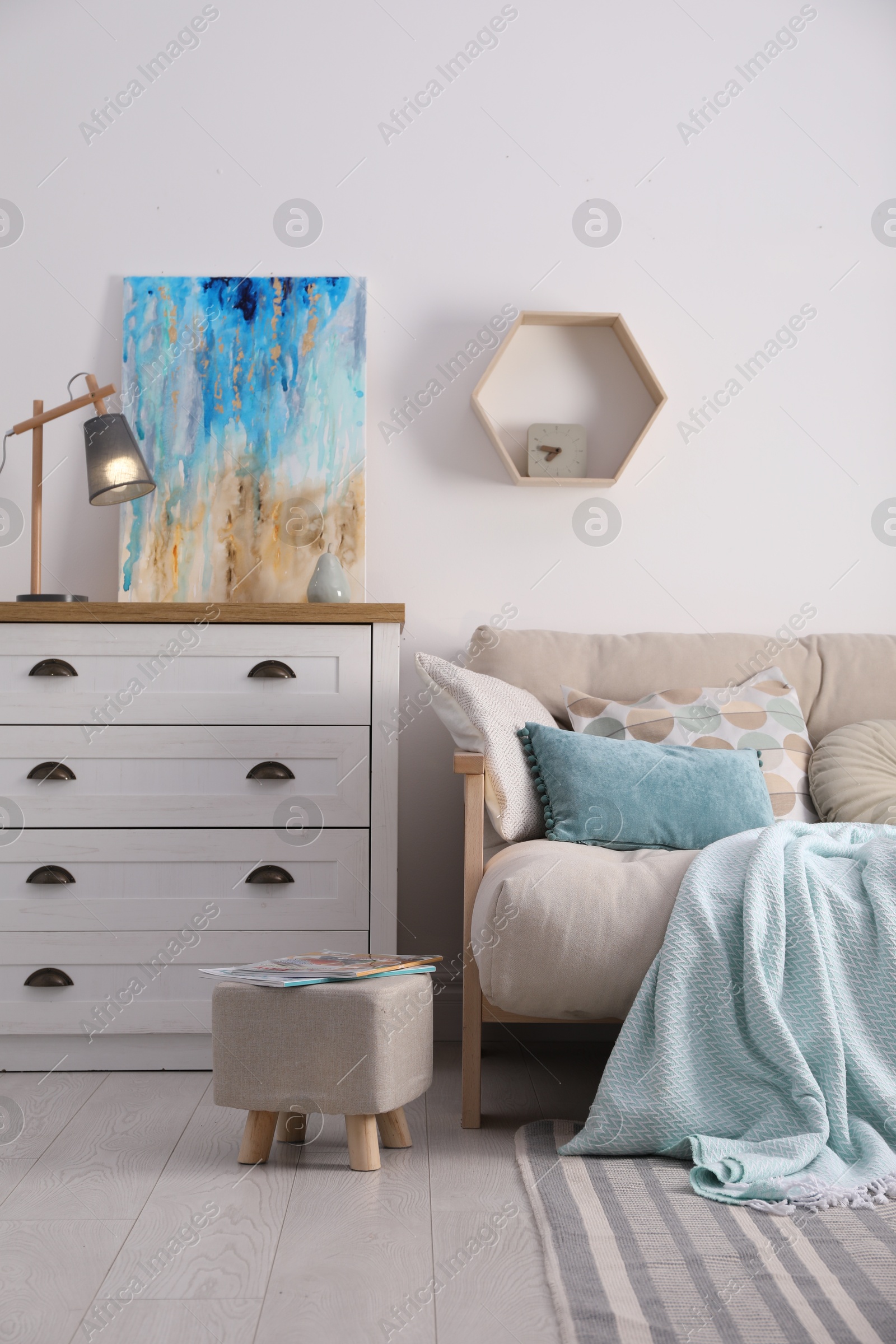 Photo of Stylish living room interior with ottoman, sofa and white wooden chest of drawers