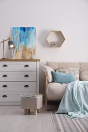 Photo of Stylish living room interior with ottoman, sofa and white wooden chest of drawers