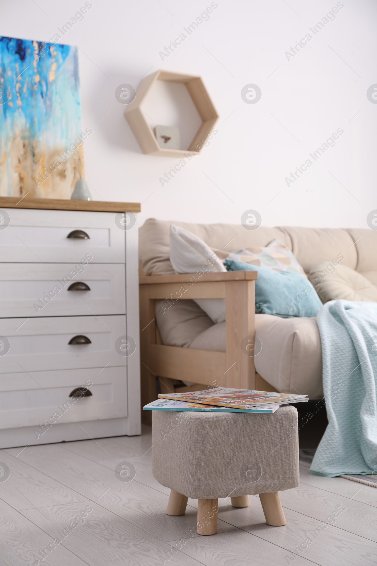 Photo of Stylish ottoman with magazines near sofa in light living room