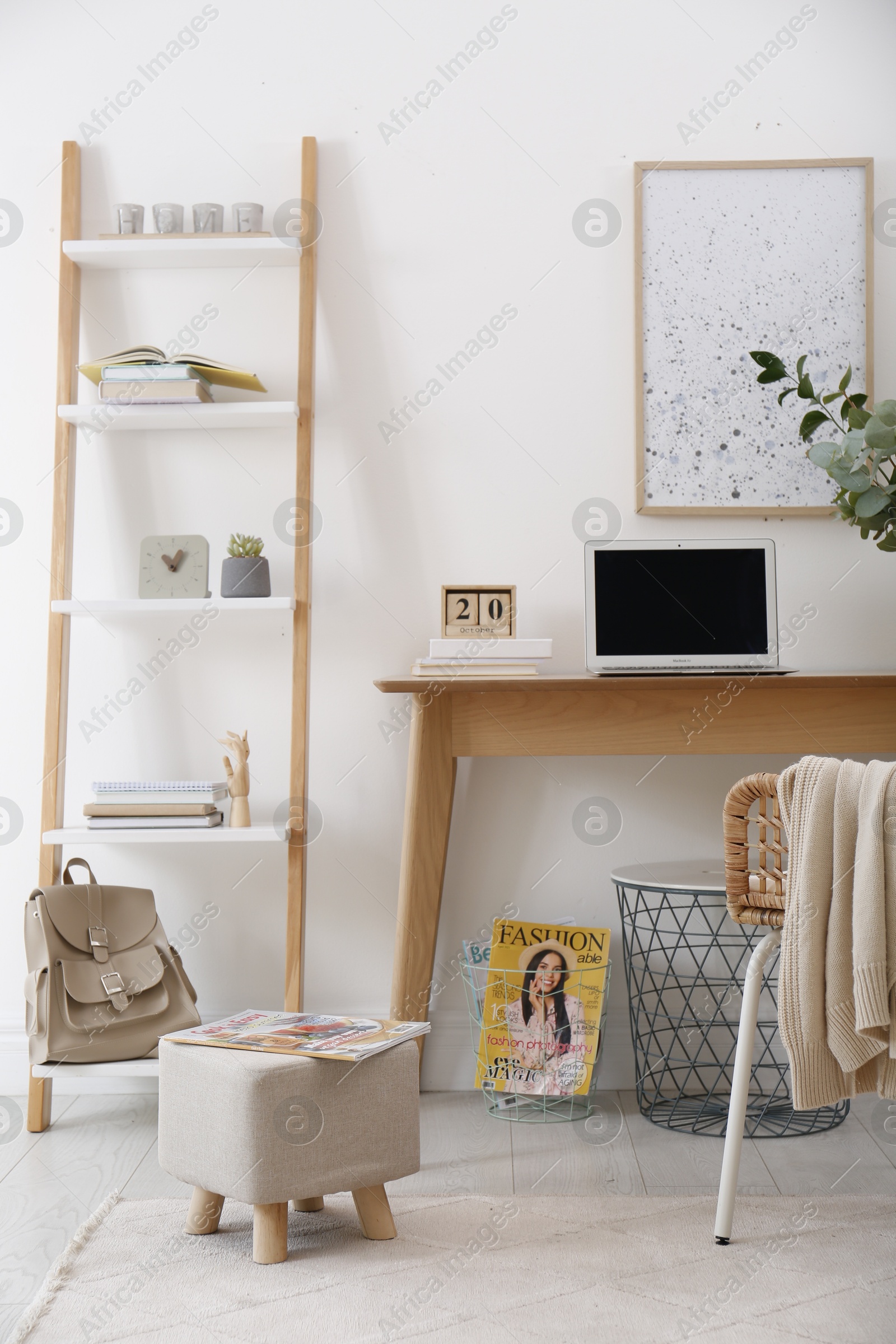 Photo of Stylish ottoman with magazine on floor in modern home office. Interior design