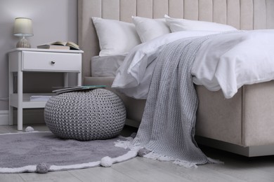 Photo of Stylish bedroom interior with knitted pouf and furniture