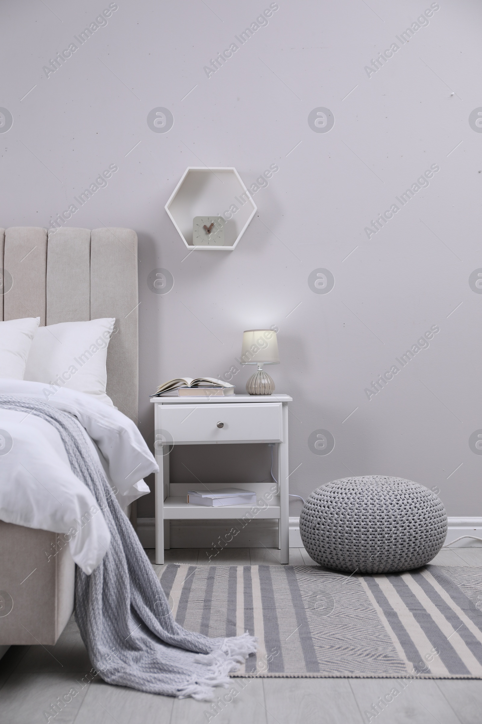 Photo of Stylish bedroom interior with knitted pouf and furniture