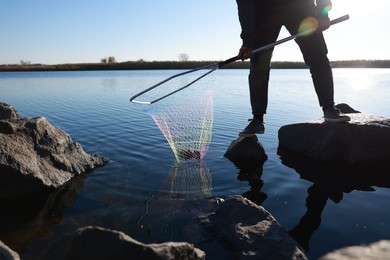 Photo of Fisherman holding fishing net with catch at riverside, closeup