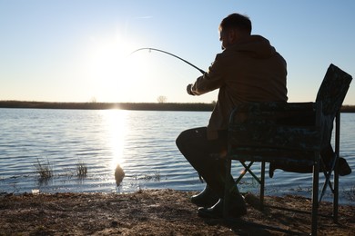 Photo of Fisherman catching fish with rod at riverside