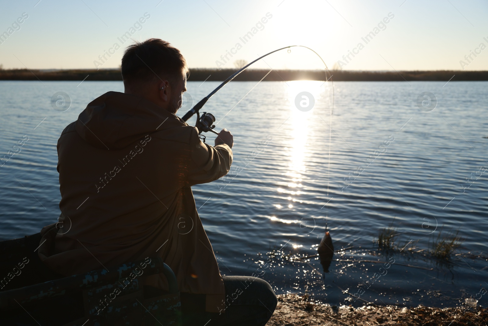 Photo of Fisherman catching fish with rod at riverside