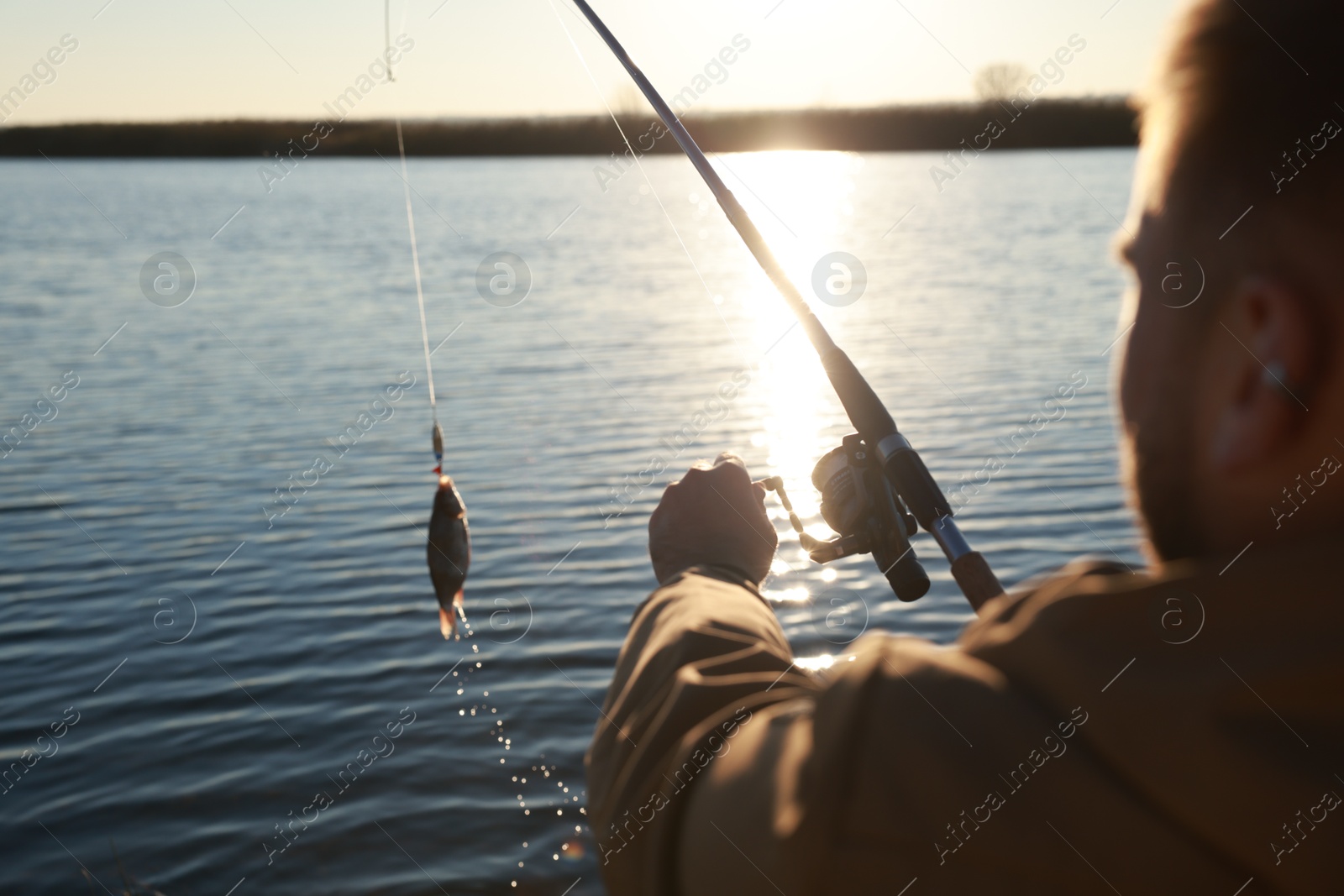 Photo of Fisherman catching fish with rod at riverside, closeup