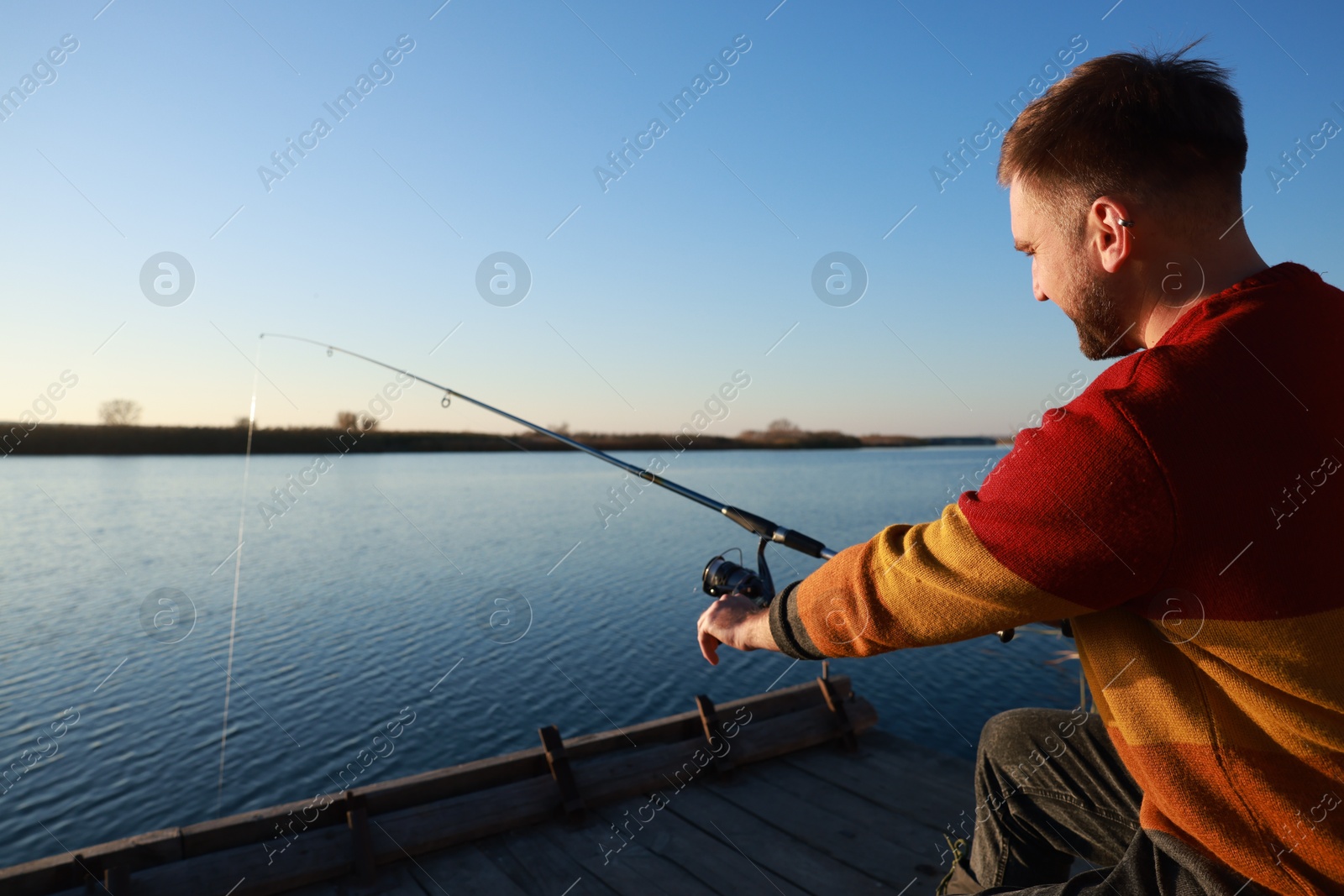 Photo of Fisherman with fishing rod at riverside on sunny day