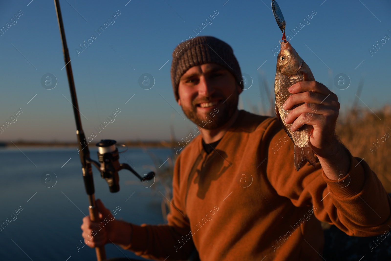 Photo of Fisherman with rod and caught fish at riverside