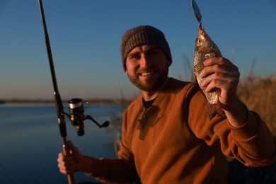 Photo of Fisherman with rod and caught fish at riverside