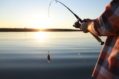 Photo of Fisherman catching fish with rod at riverside, closeup