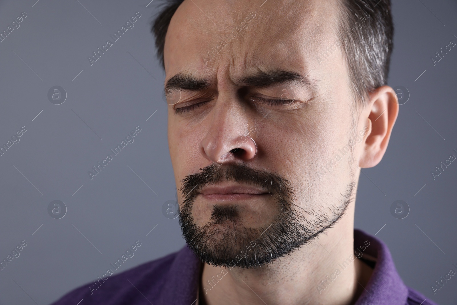 Photo of Sad man crying on grey background, closeup. Space for text