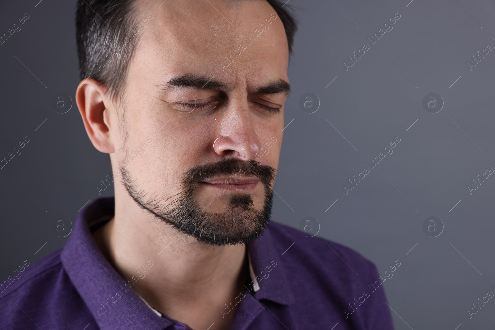 Photo of Sad man crying on grey background, space for text