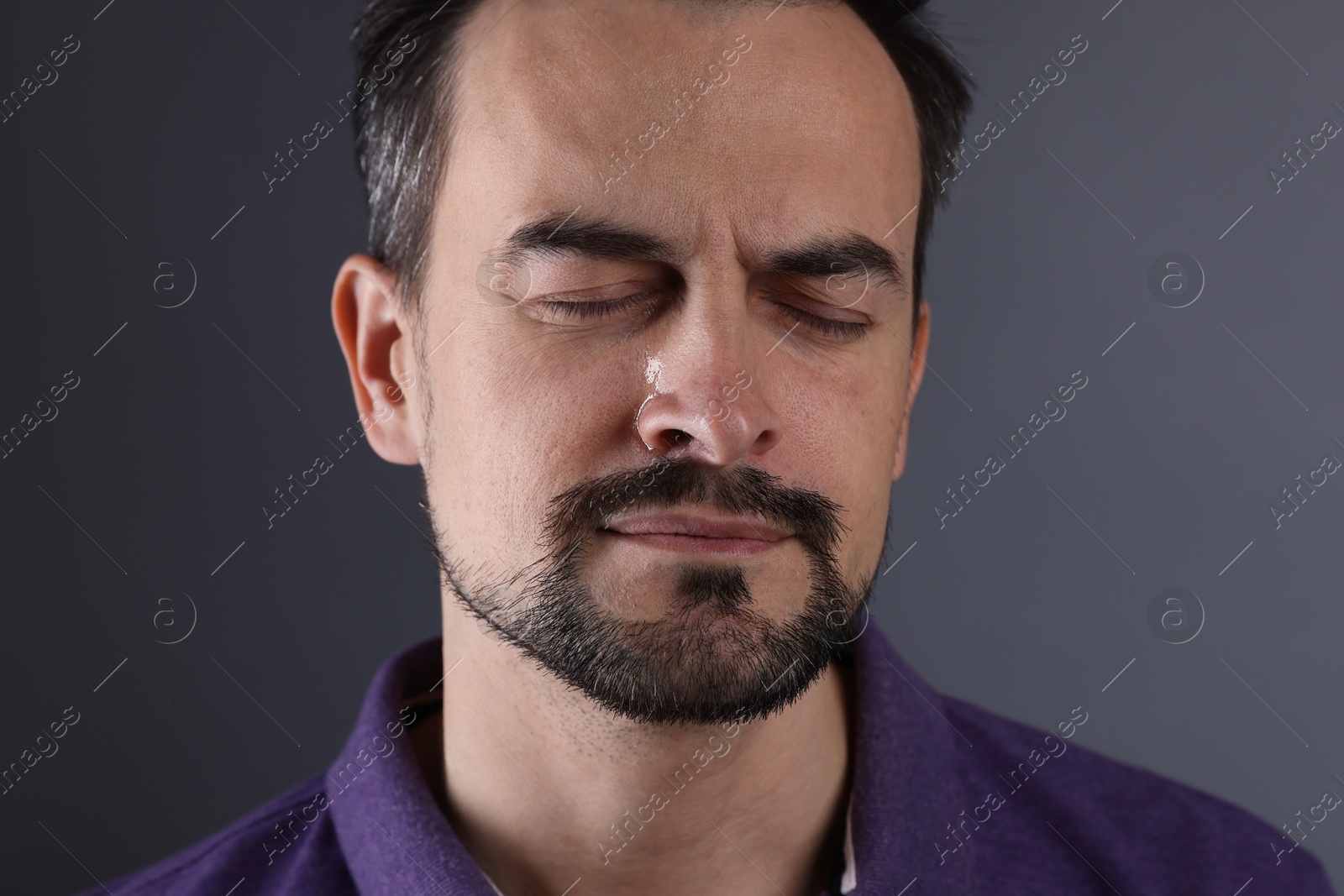 Photo of Sad man crying on grey background, closeup