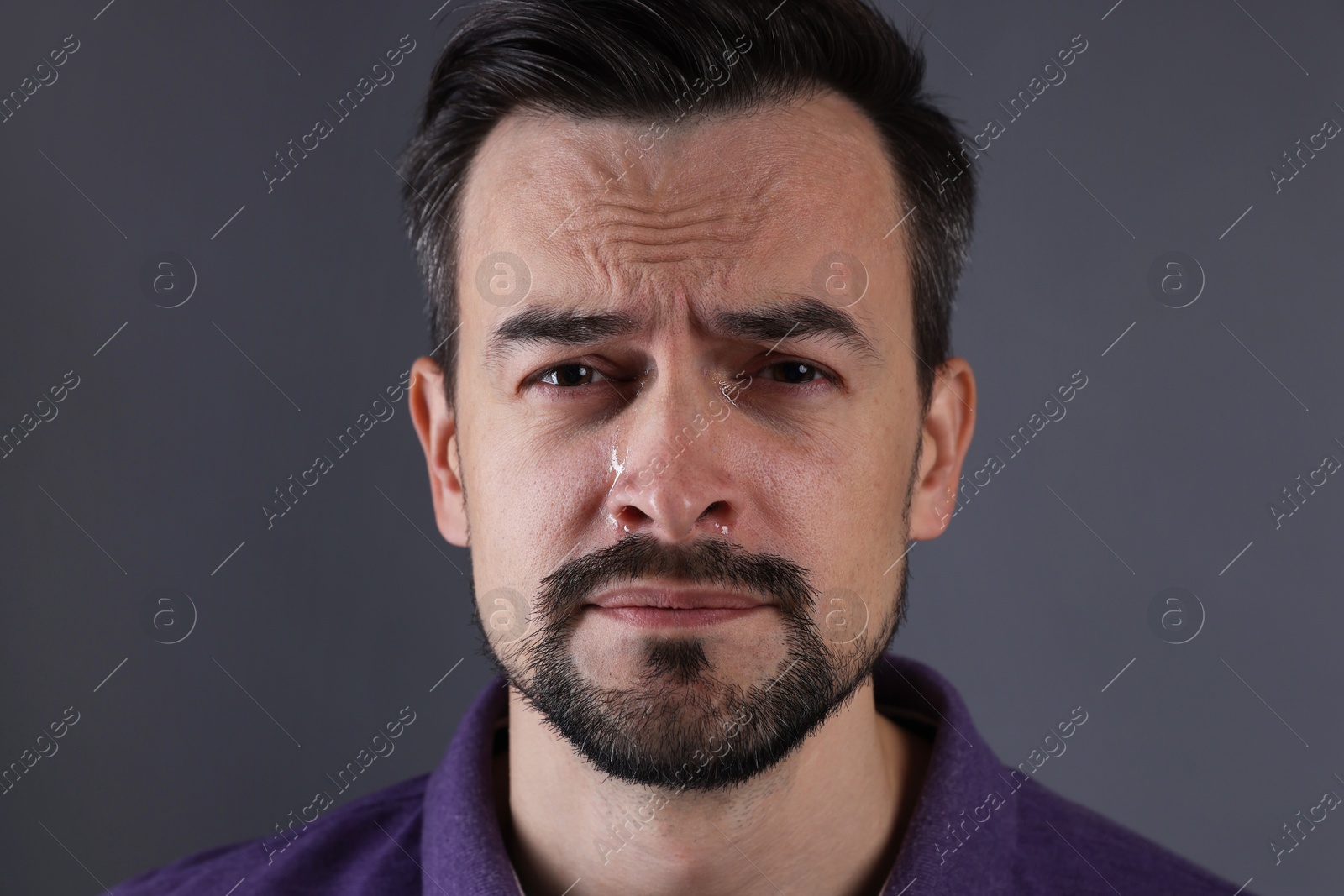 Photo of Portrait of sad man crying on grey background