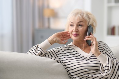 Photo of Beautiful grandmother talking on smartphone at home. Space for text