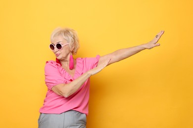 Photo of Portrait of cool grandmother in sunglasses on orange background