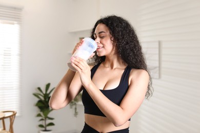 Photo of Beautiful woman drinking protein shake at home