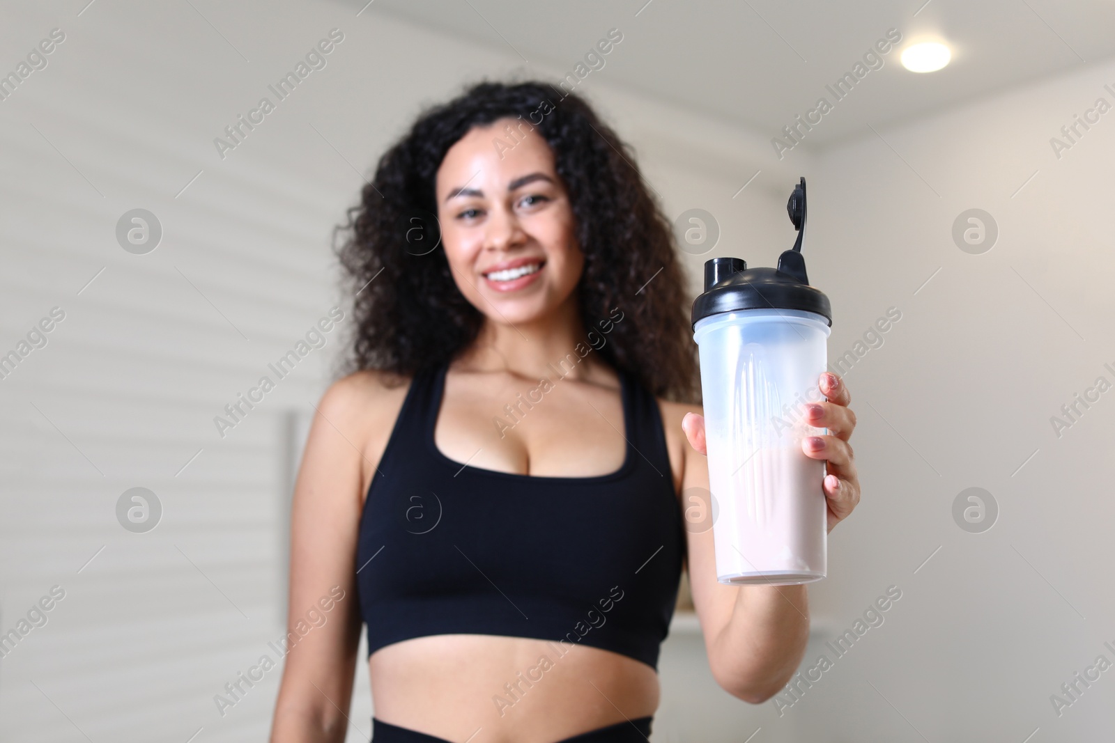 Photo of Beautiful woman with protein shake at home, selective focus