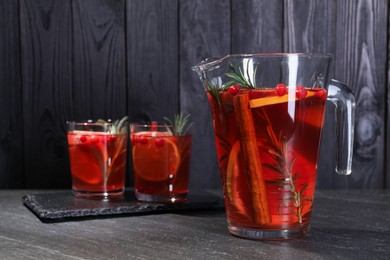 Photo of Delicious punch in jug and glasses on black table