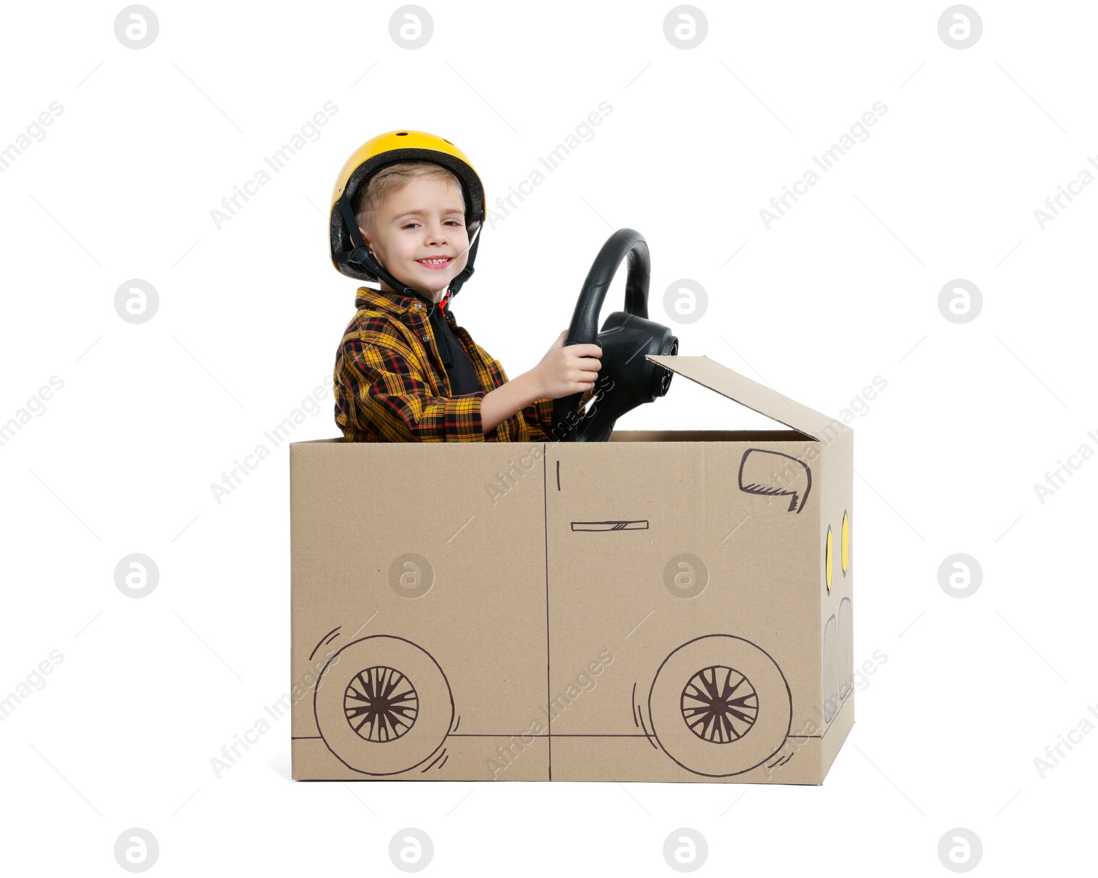 Photo of Little boy driving car made of cardboard on white background