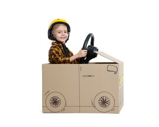 Photo of Little boy driving car made of cardboard on white background