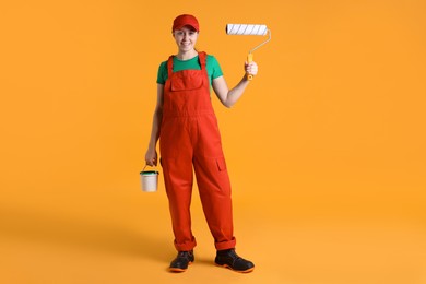 Photo of Professional painter with roller and bucket of paint on orange background