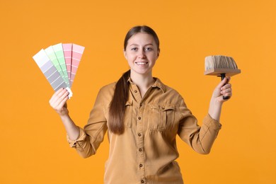 Photo of Woman with paintbrush and color selection chart on orange background