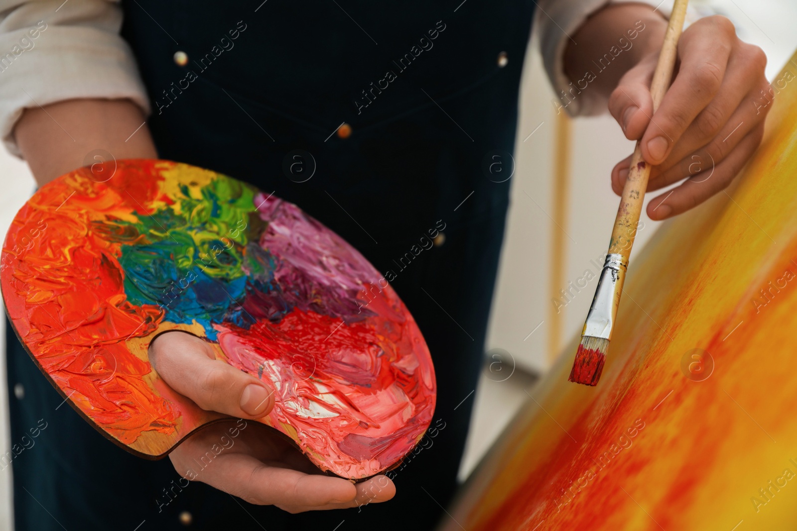 Photo of Man with palette and paintbrush drawing picture indoors, closeup