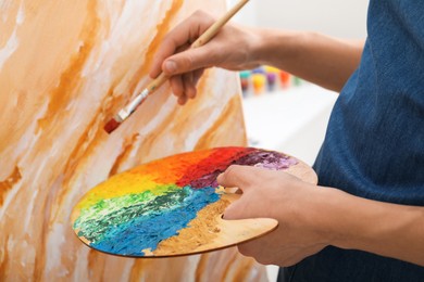 Photo of Man with palette and paintbrush drawing picture, closeup