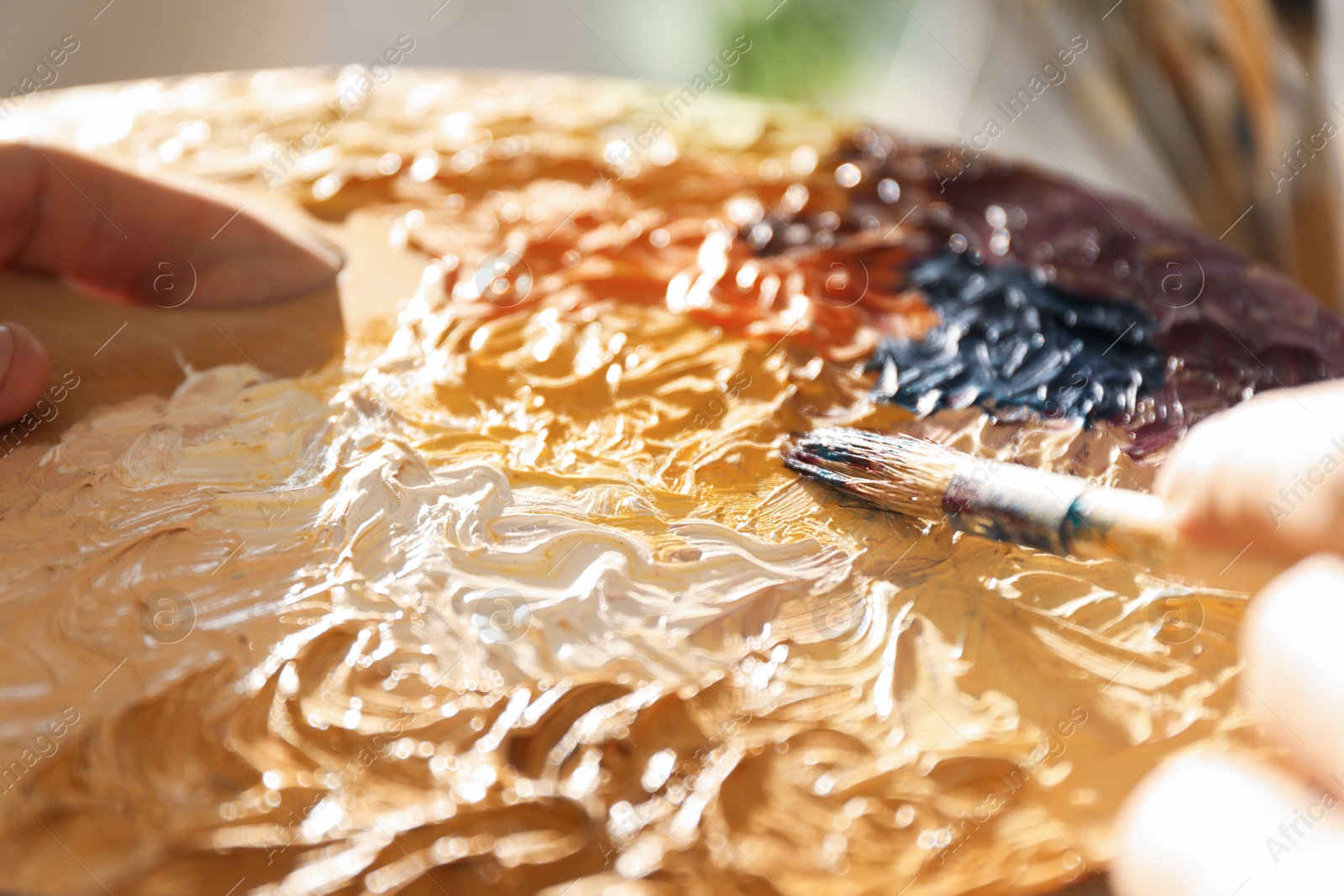 Photo of Man with paintbrush mixing paints on palette, closeup