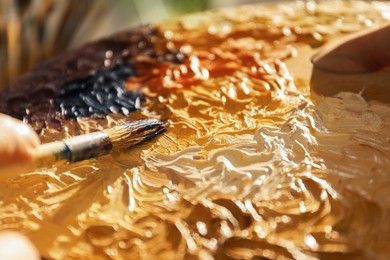 Photo of Mixing paints with brush on palette, closeup