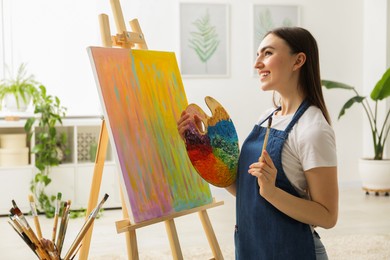 Photo of Smiling woman with palette and paintbrush drawing abstract picture