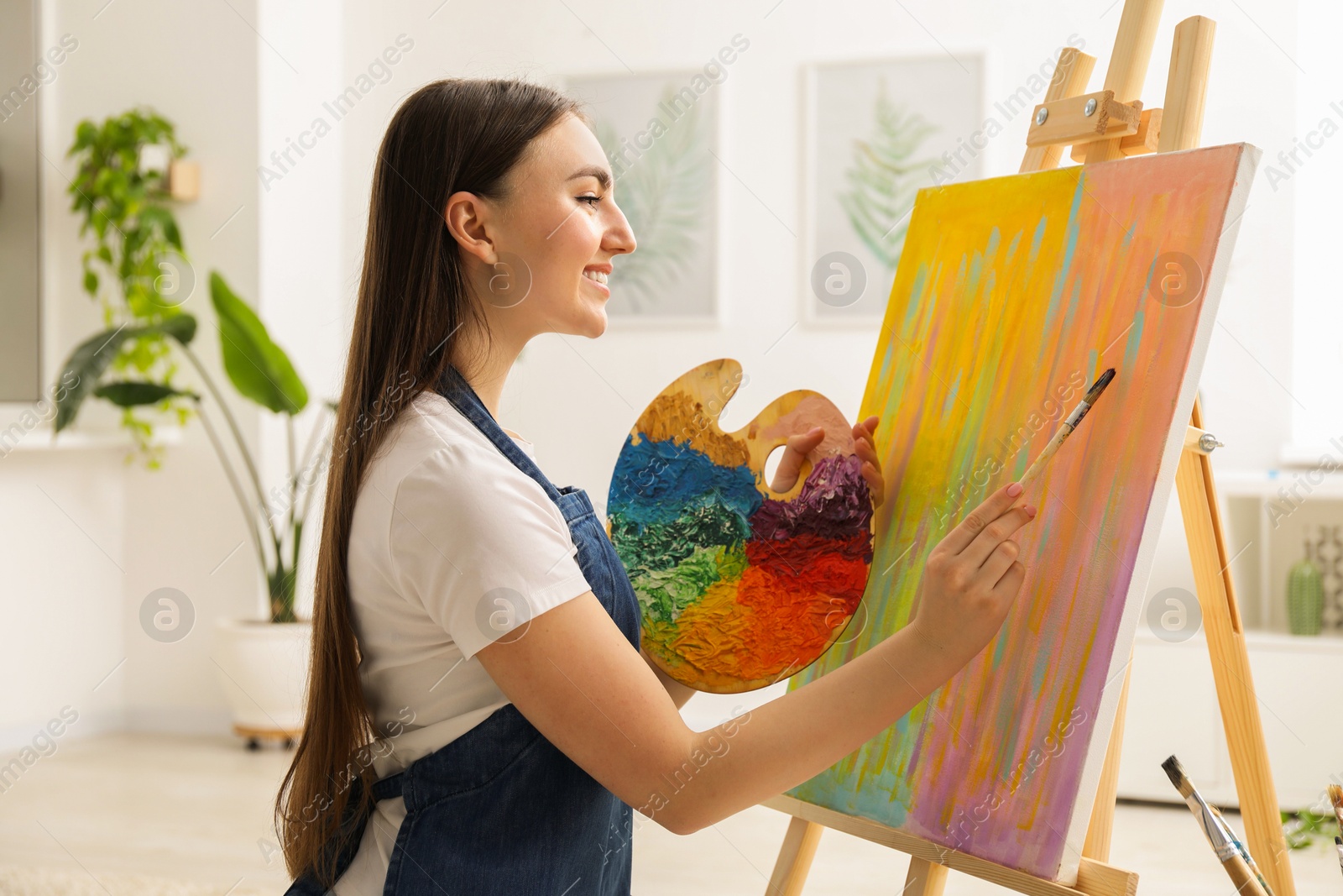 Photo of Smiling woman with palette and paintbrush drawing abstract picture