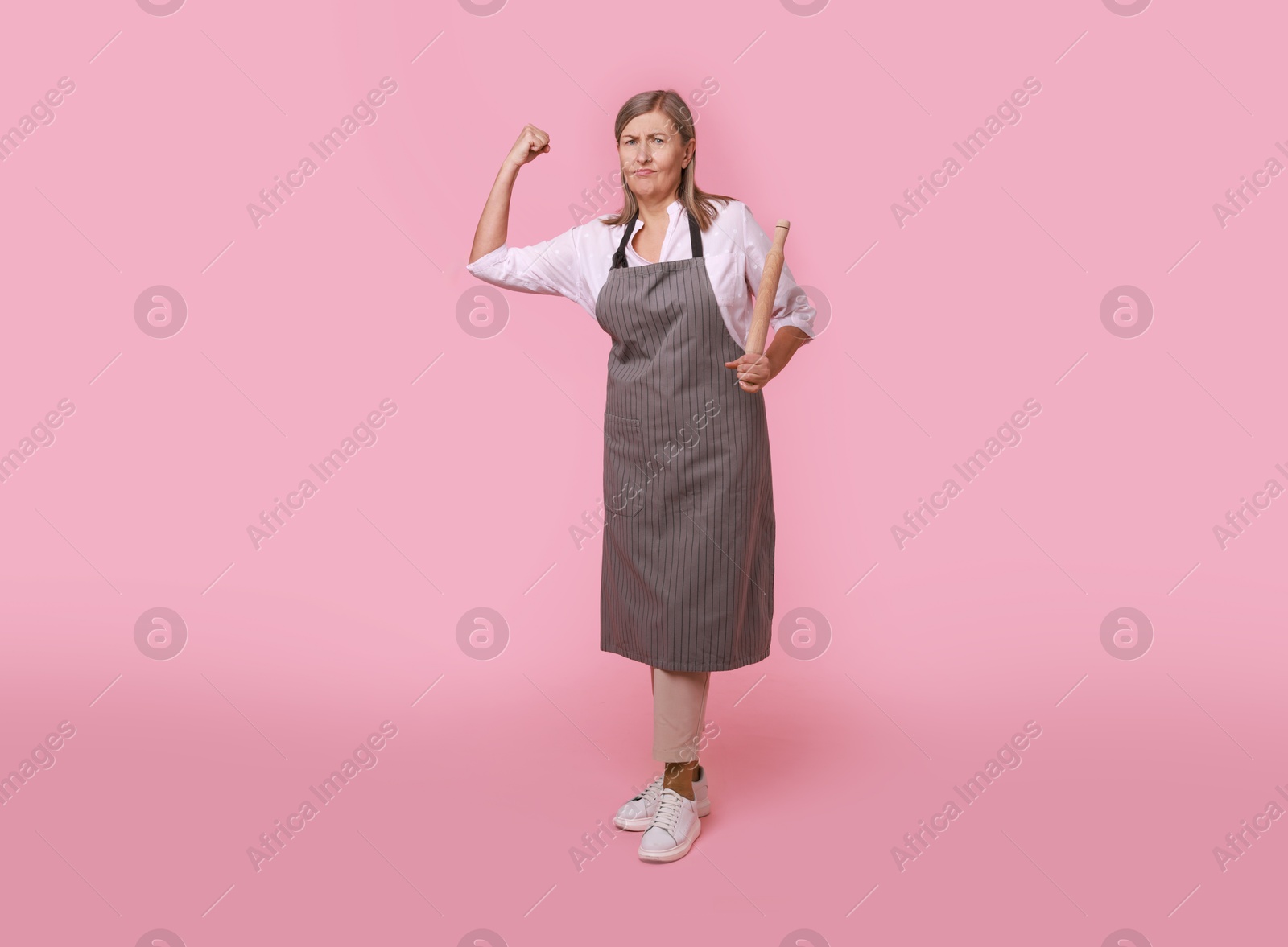 Photo of Emotional woman with rolling pin on pink background