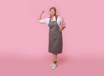 Photo of Emotional woman with rolling pin on pink background