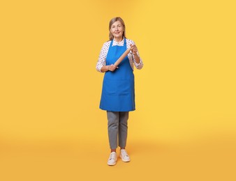 Photo of Happy woman with rolling pin on yellow background