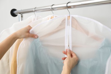 Photo of Woman zipping garment cover with clothes indoors, closeup