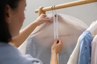 Photo of Woman zipping garment cover with clothes indoors, closeup