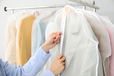 Photo of Woman zipping garment cover with clothes indoors, closeup