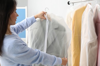 Woman holding garment cover with clothes indoors