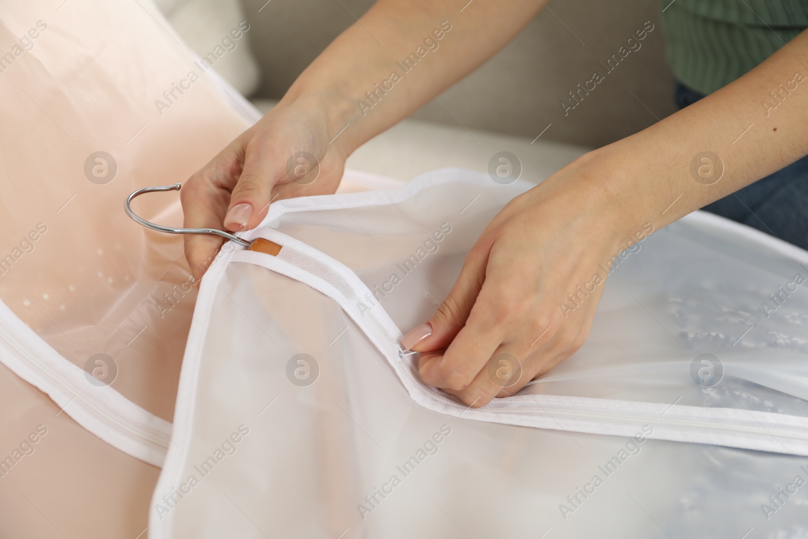 Photo of Woman zipping garment cover with clothes indoors, closeup