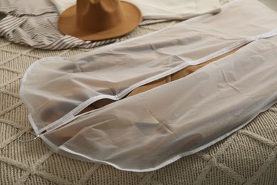 Photo of Garment cover with clothes on bed indoors, closeup