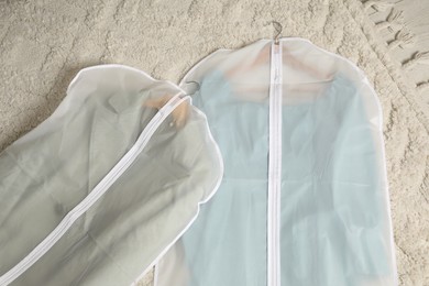 Photo of Garment covers with clothes on floor indoors, top view